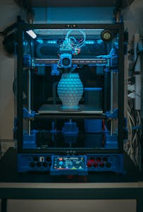 Close-up of a 3D printer in action, crafting a detailed vase in a modern setting.